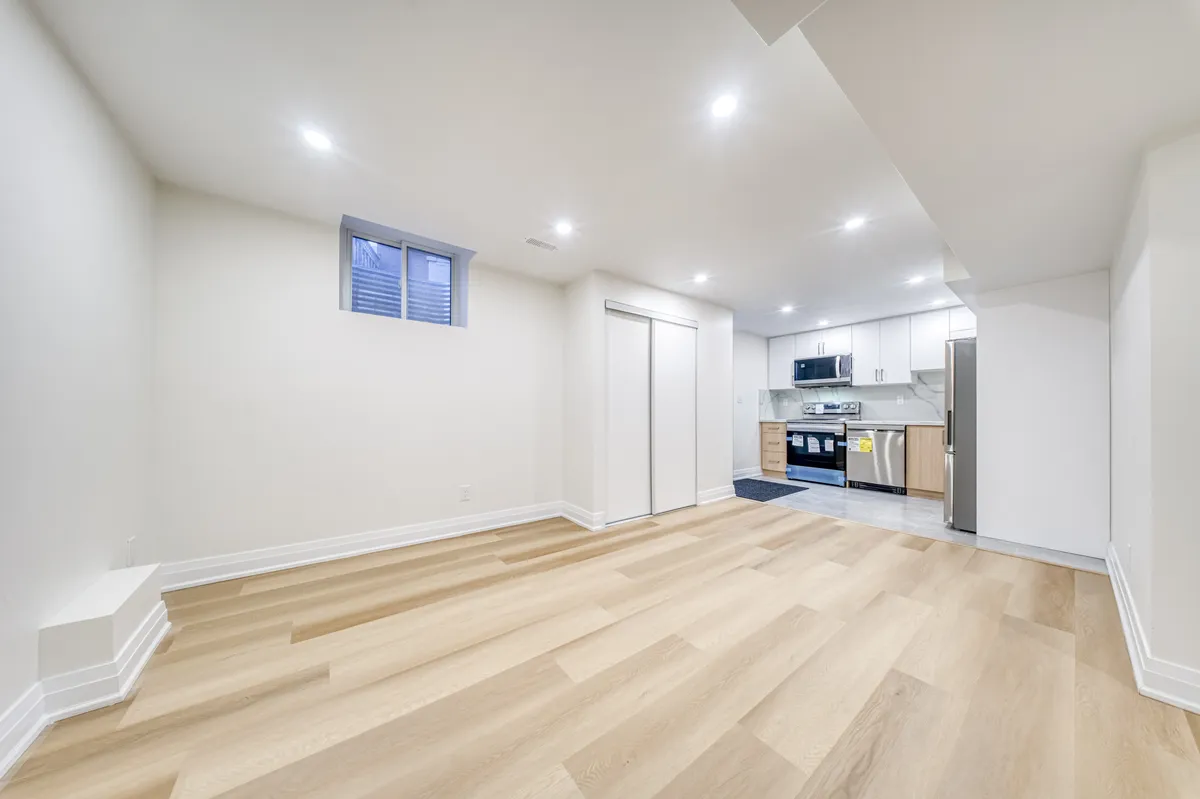 The finished basement: plank floors, pot lights and a kitchen at the far end.