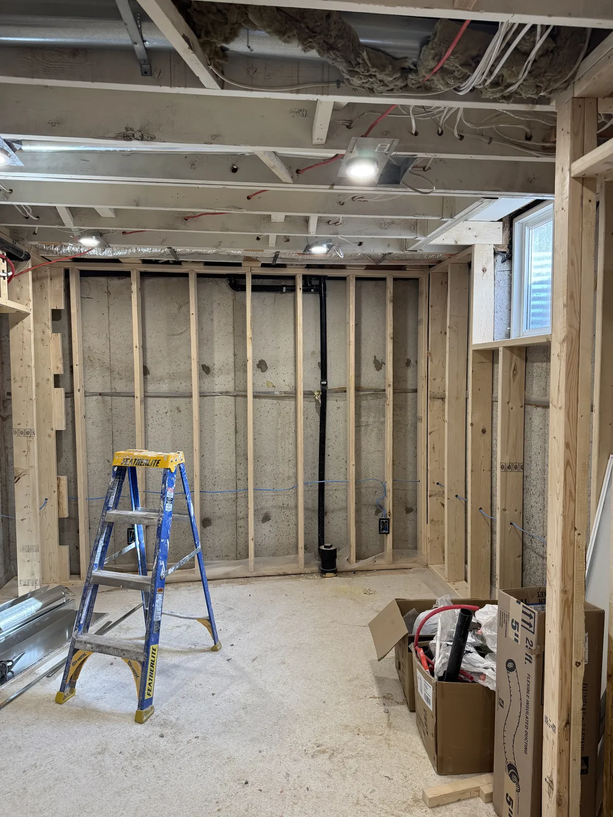 The basement mid-renovation: new stud walls, plumbing stacks and open joists.