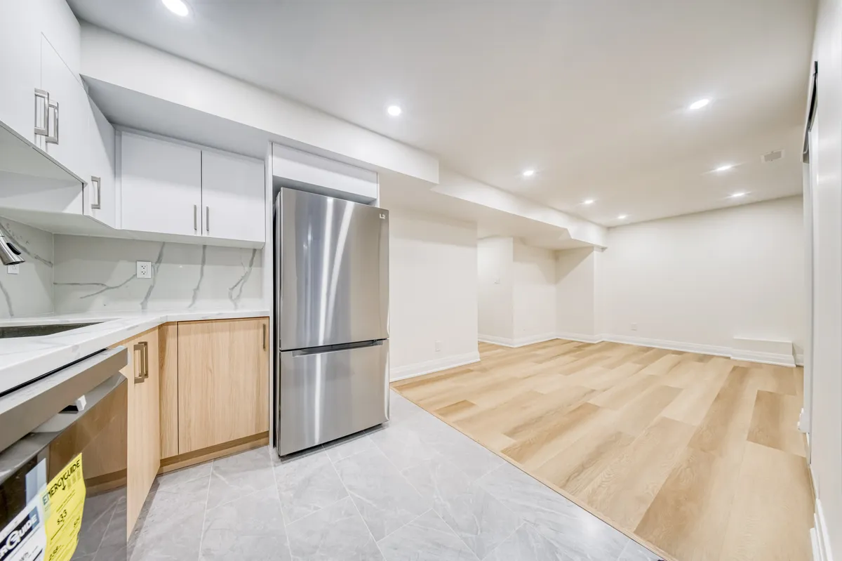 The basement kitchen: oak lowers, white uppers and a steel fridge, open to the living space.
