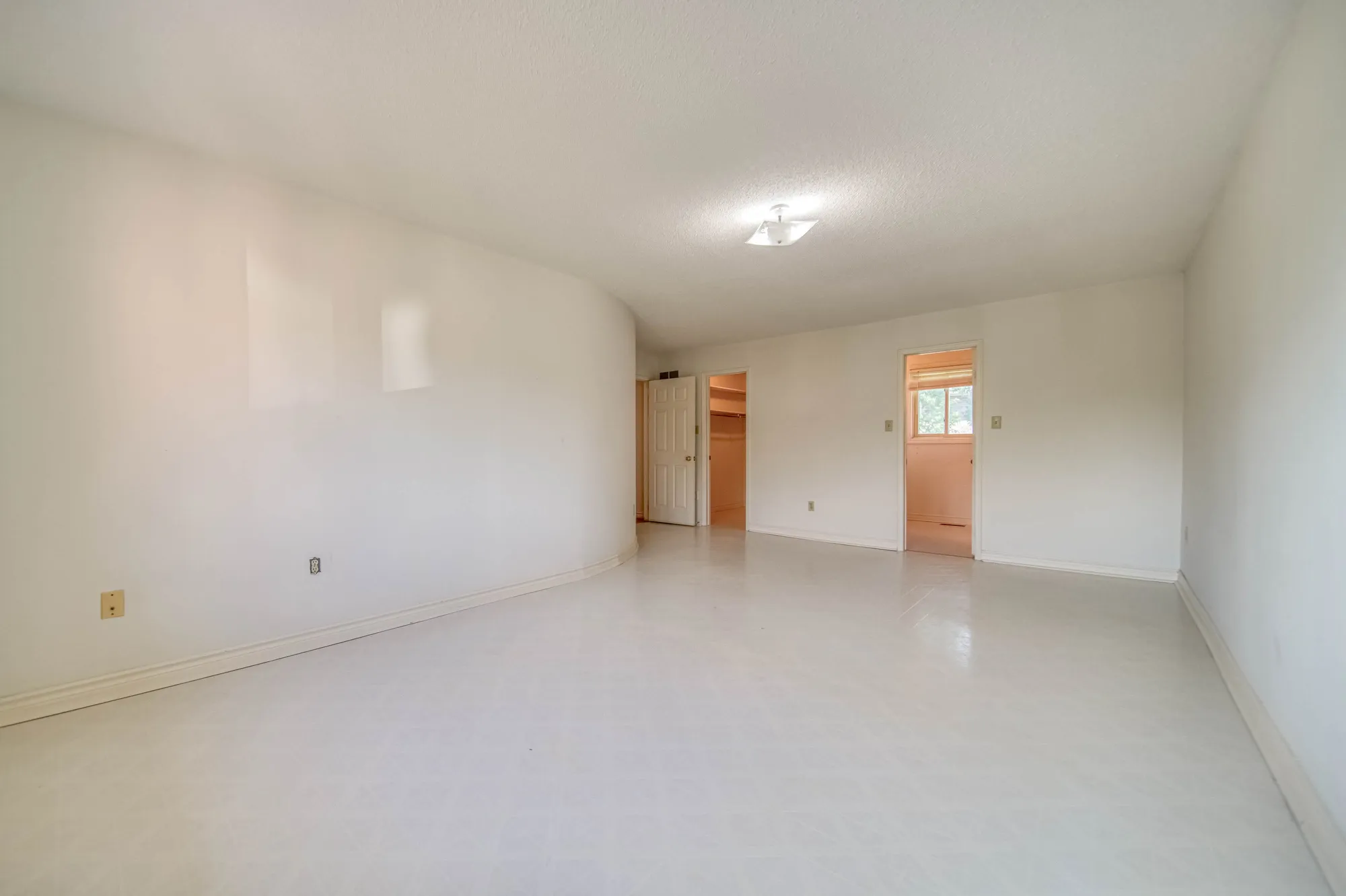 The primary bedroom before: an empty room with a vinyl floor.