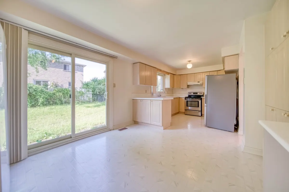 The kitchen before: maple cabinets, a tiled floor and a sliding door to the yard.