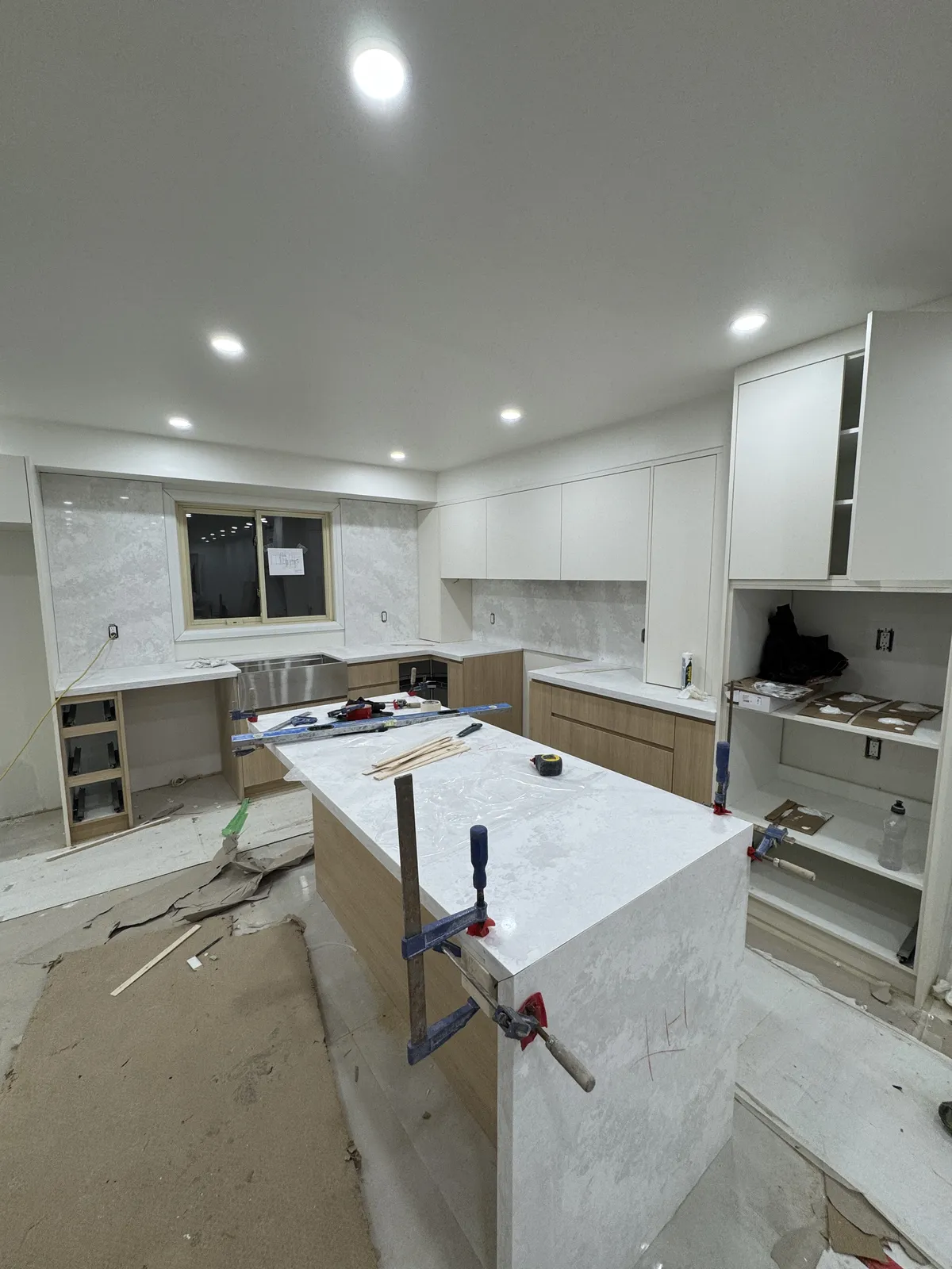 The kitchen mid-renovation: cabinets in, the stone island clamped while it sets.