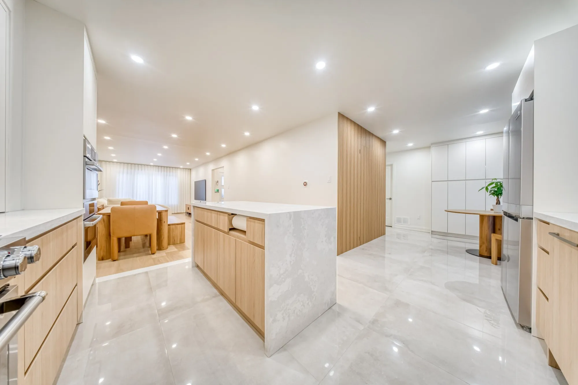 An open kitchen with a stone waterfall island, looking through to the dining and living rooms.